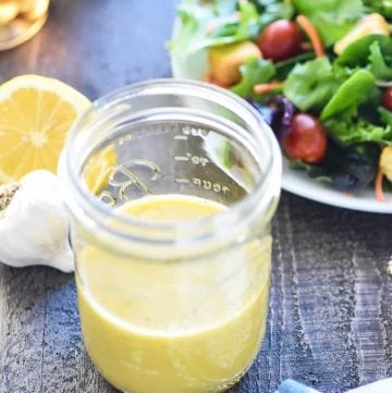 Champagne Vinaigrette recipe on table with ingredients to make it and salad in background.