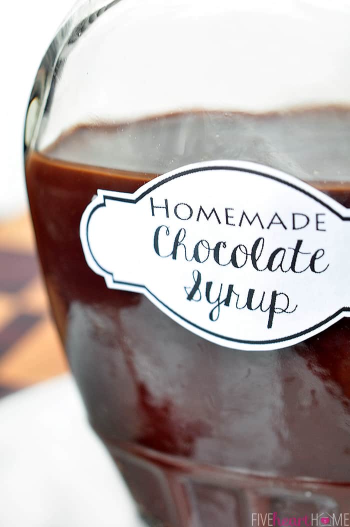 Easy Homemade Chocolate Syrup ~ this chocolate syrup recipe is made with five simple ingredients in about five minutes. It's a scrumptious topping for ice cream and makes perfect chocolate milk. And not only is it economical, but it also doesn't contain the additives and preservatives found in many store-bought brands! | FiveHeartHome.com Chocolate Syrup recipe in a labeled
glass bottle.