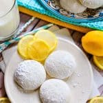 Aerial view of Lemon Cooler Cookies on a plate, with decorative lemon slices and a glass of milk