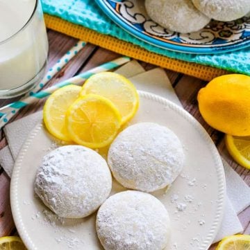 Aerial view of Lemon Cooler Cookies on a plate, with decorative lemon slices and a glass of milk