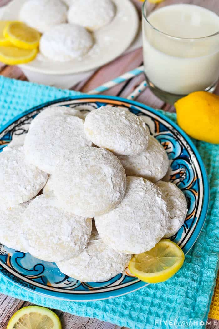 Lemon Cooler Cookies ~ soft, tender cookies bursting with fresh lemon and real butter, then coated in lemony powdered sugar! | FiveHeartHome.com Teal kitchen towel and decorative plate piled with Lemon Cooler Cookies.