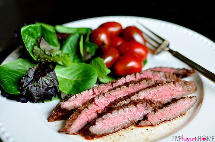 Plate with grilled flank steak, salad, tomatoes, and a fork