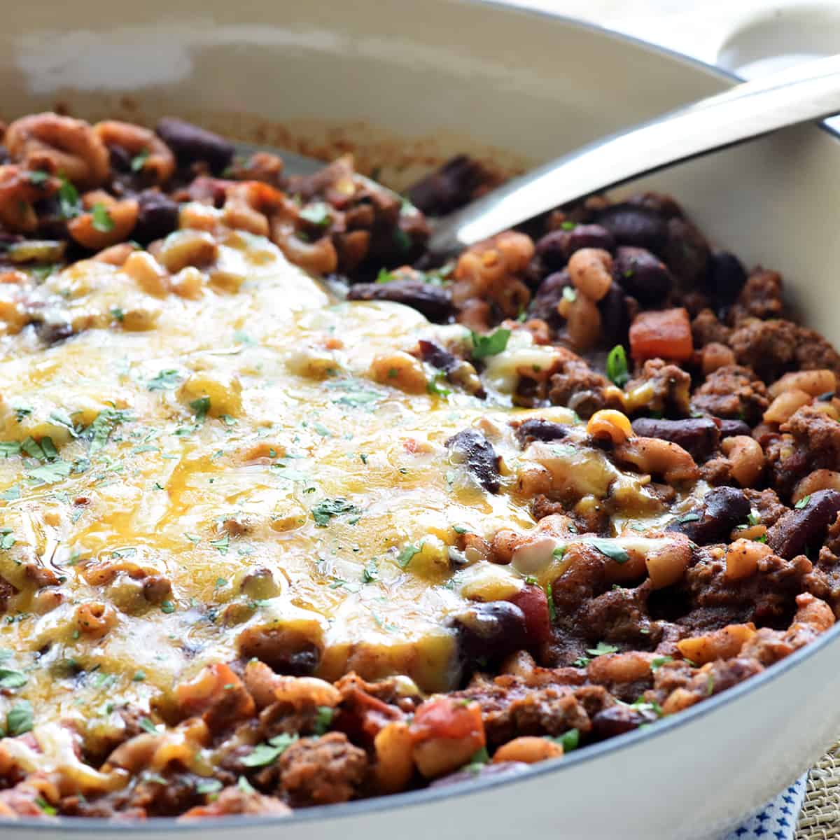 Chili Mac recipe in skillet topped with melted cheese.