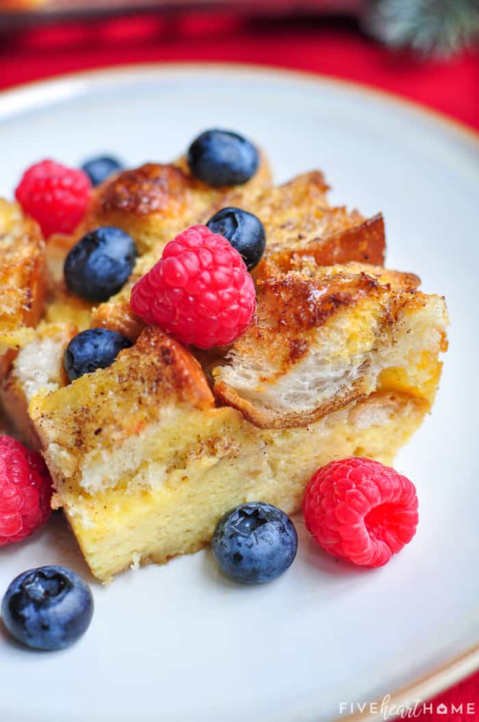 Slice of Eggnog French Toast casserole on a plate topped with berries.