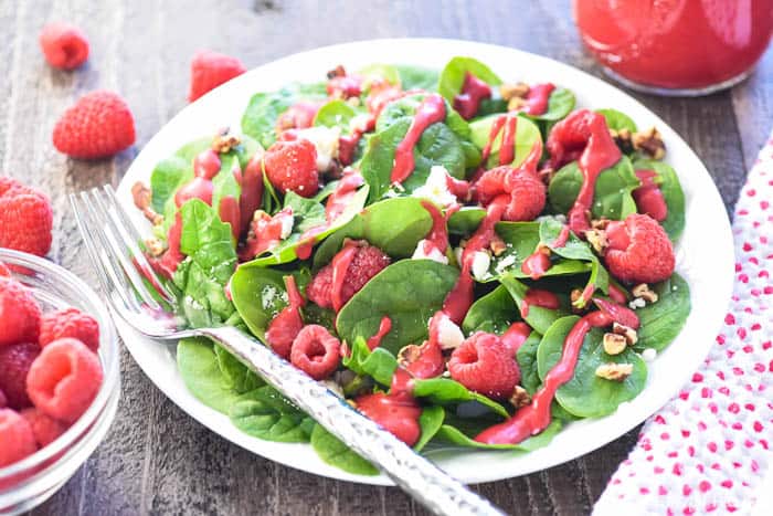 Jar of dressing and salad on plate.