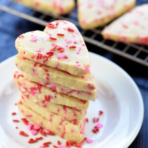 Easy Shortbread Heart-Shaped Cookies stacked on a white plate.