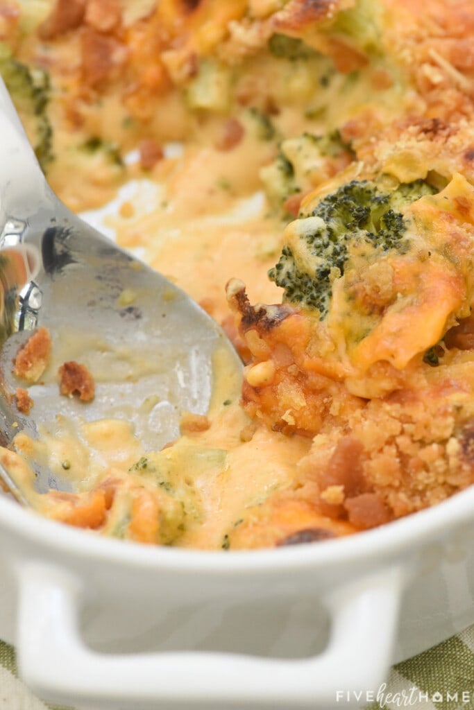 Serving spoon scooping Broccoli Cheese Casserole from dish.