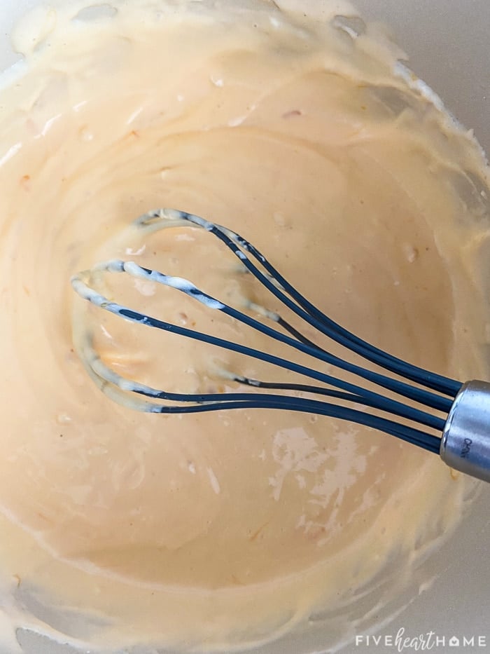 Homemade cheese sauce in pot with whisk.