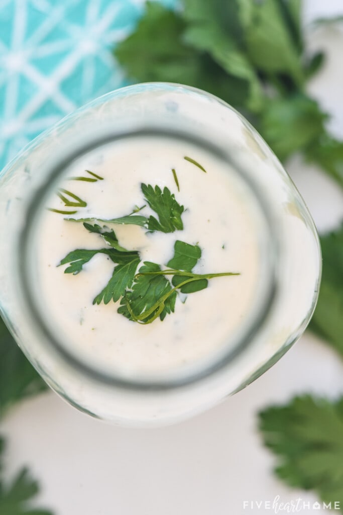 Aerial view of ranch recipe in bottle sprinkled with fresh herbs.