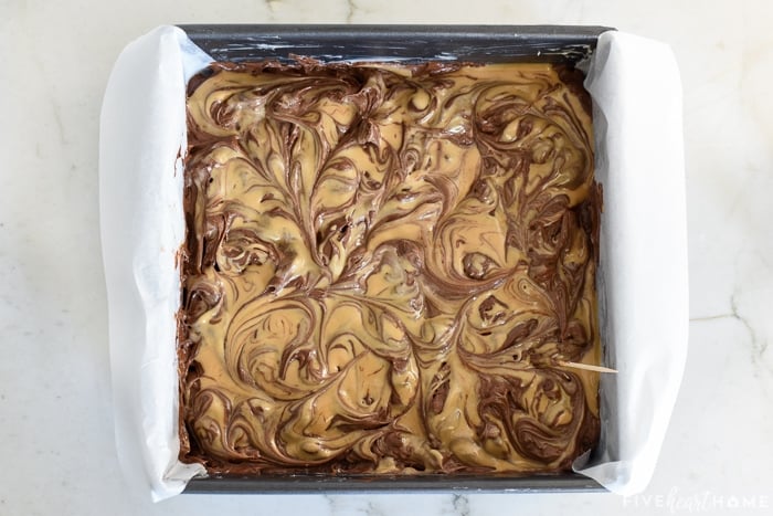 Aerial view of peanut butter swirled into surface of brownie batter.