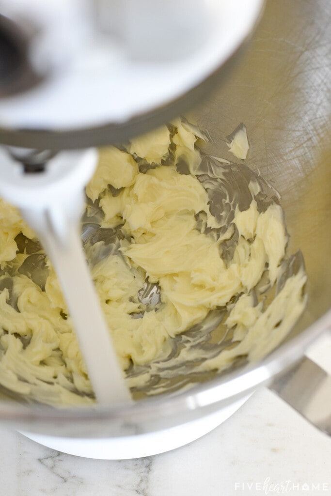 Stand mixer with creamed butter in bowl.