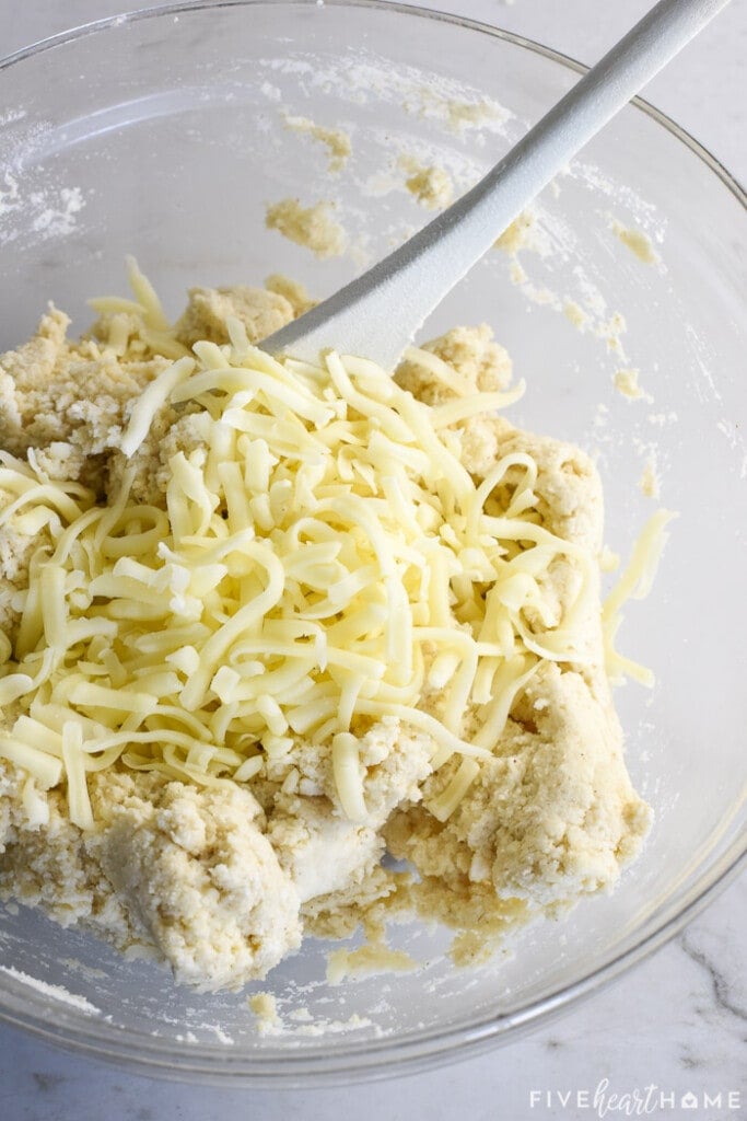 Shredded cheese being mixed into masa mixture.