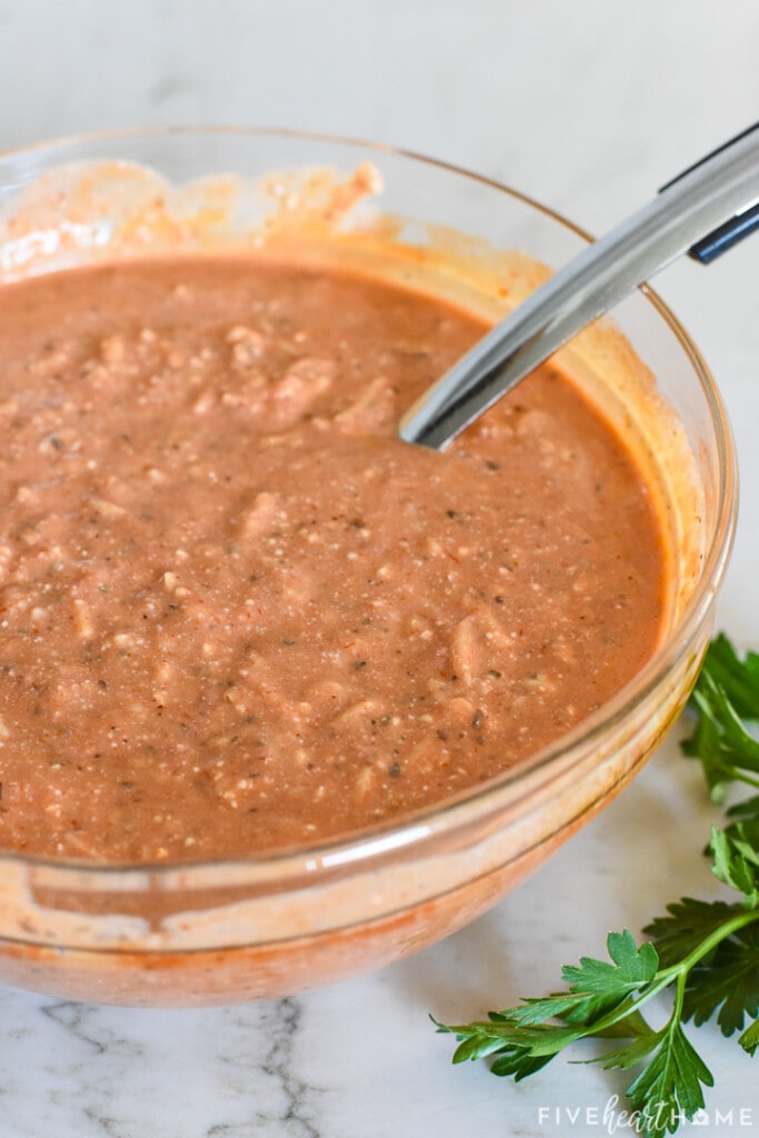 Glass bowl of sauce with spoon.