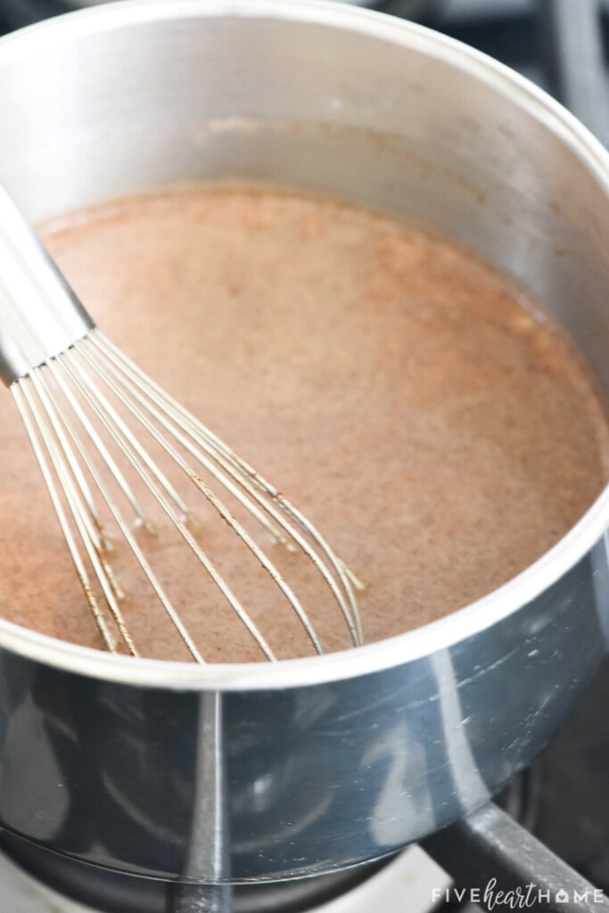 Pumpkin cream mixture being whisked in pot on stove.