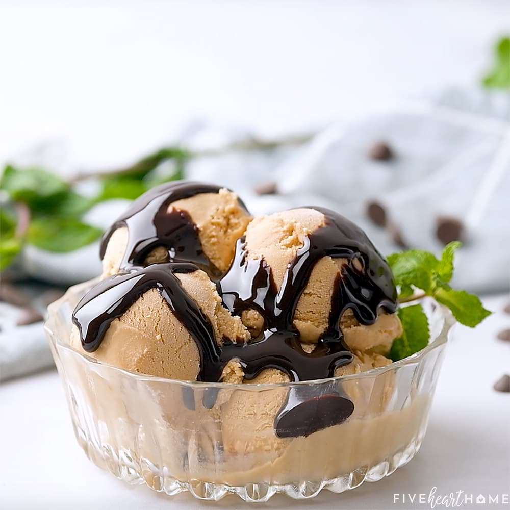 Chocolate syrup over ice cream in glass bowl.