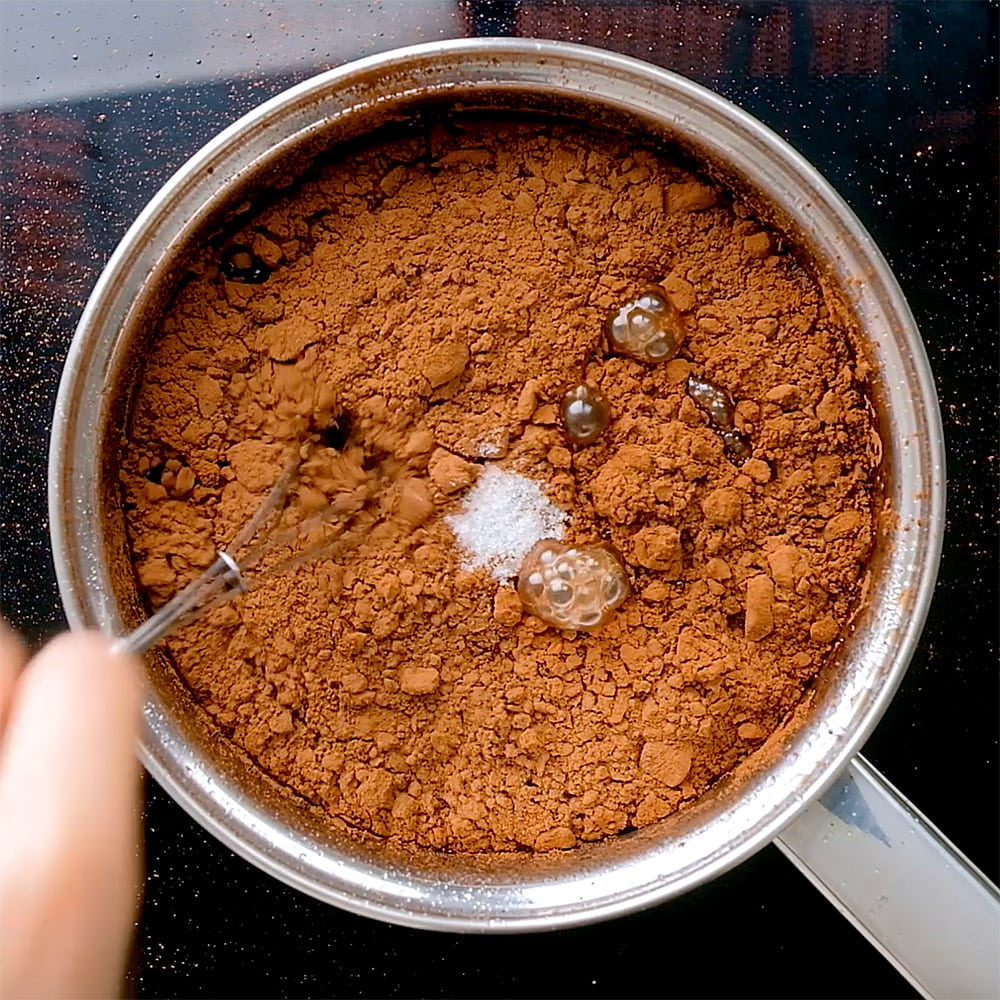 Cocoa and salt being stirred into simple syrup.