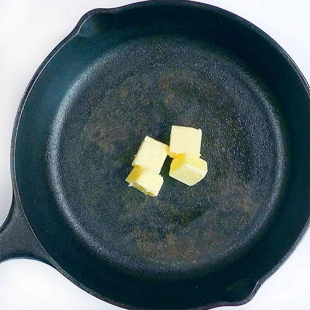 Cast iron skillet with cubes of butter.