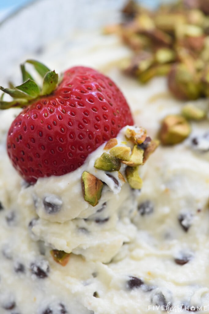 Close-up of strawberry dipping up Cannoli Dip.