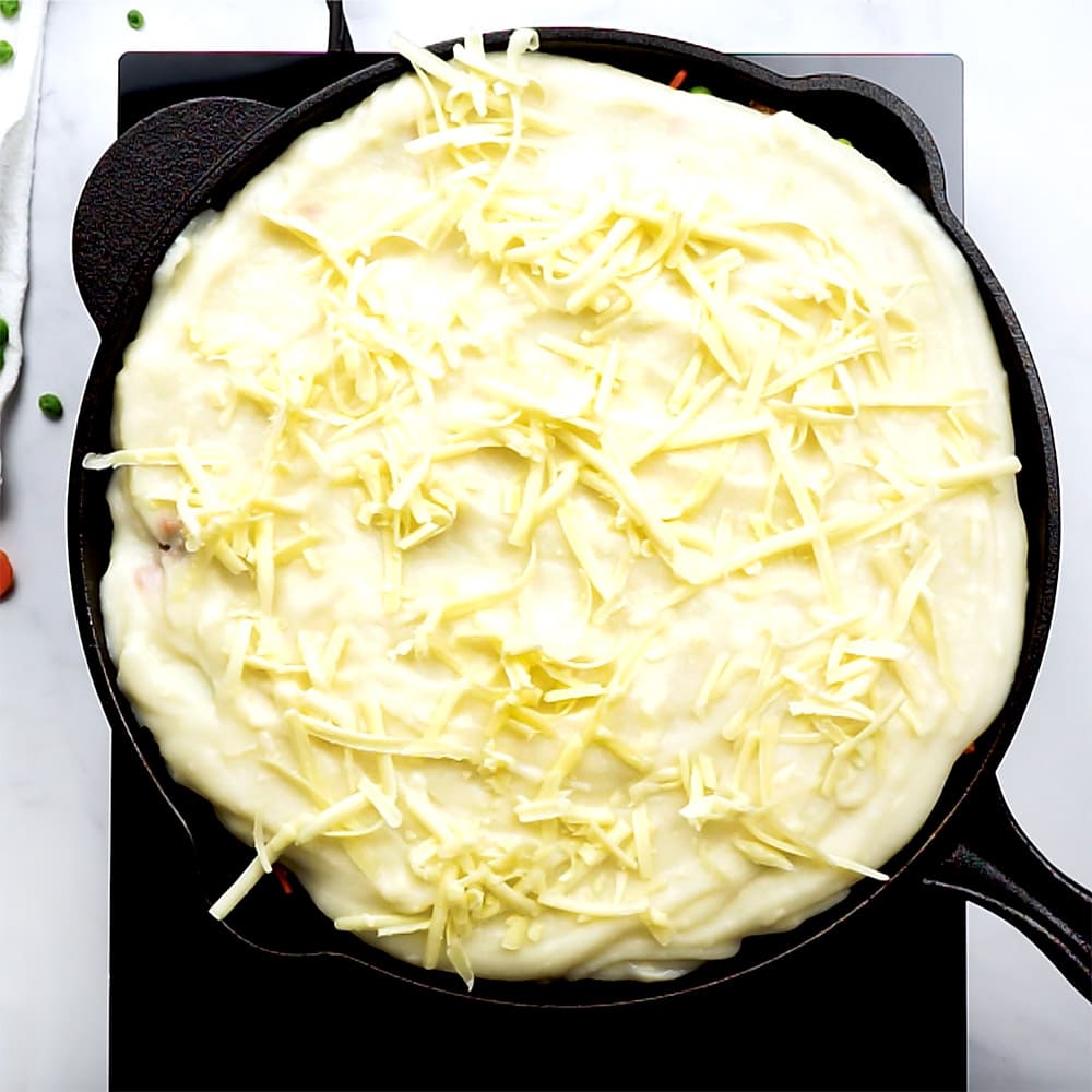 Mashed potatoes and cheese on top of skillet.