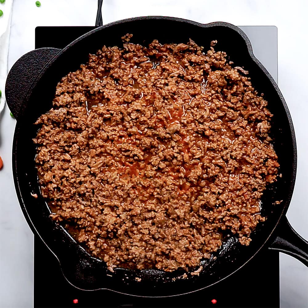 Seasoned ground beef in skillet ready for vegetables.