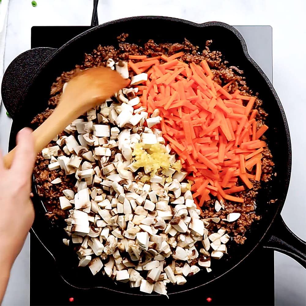 Garlic, carrots, and mushrooms added to skillet.