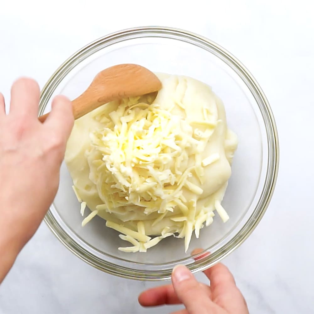 Stirring cheese into mashed potatoes.