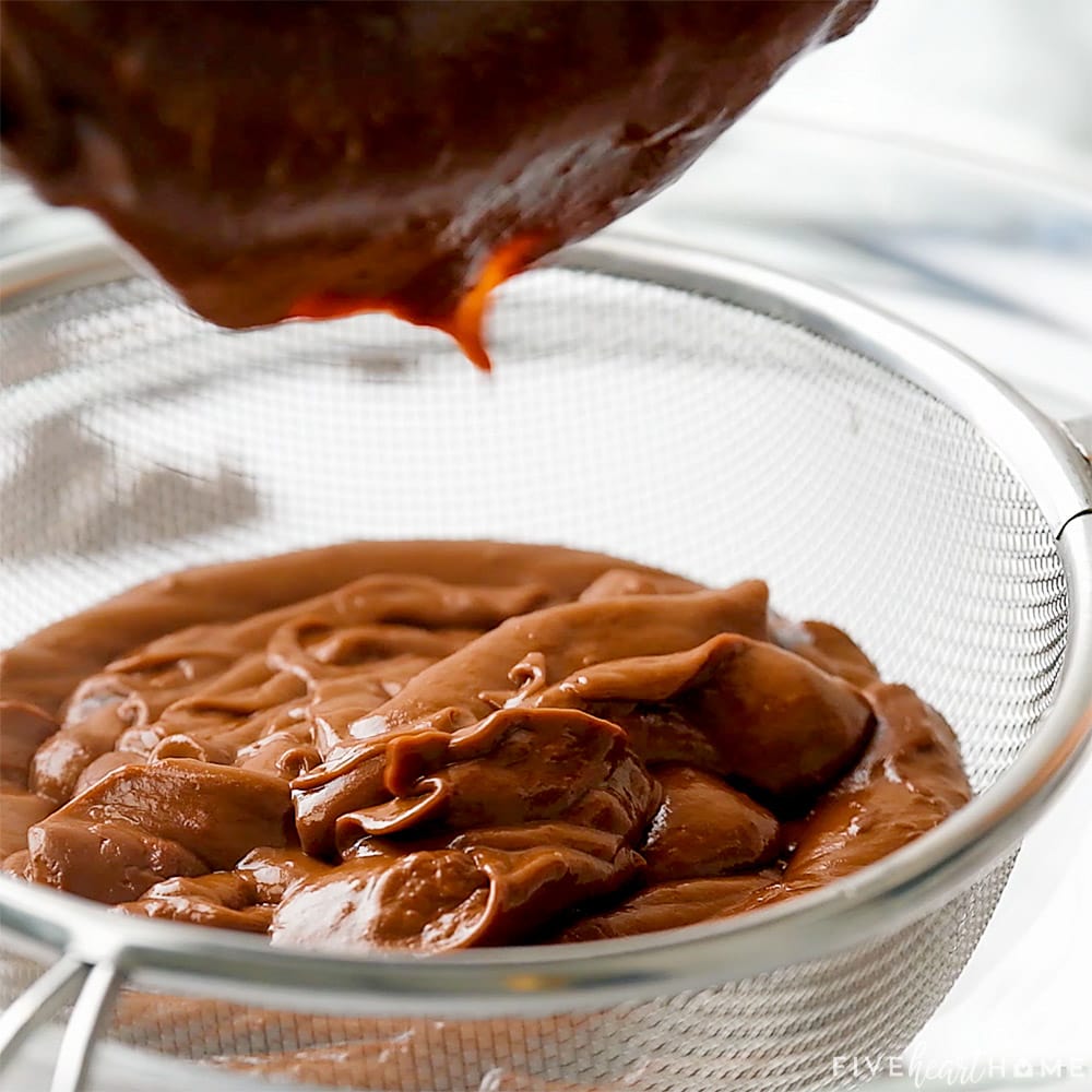 Straining chocolate pudding through sieve.