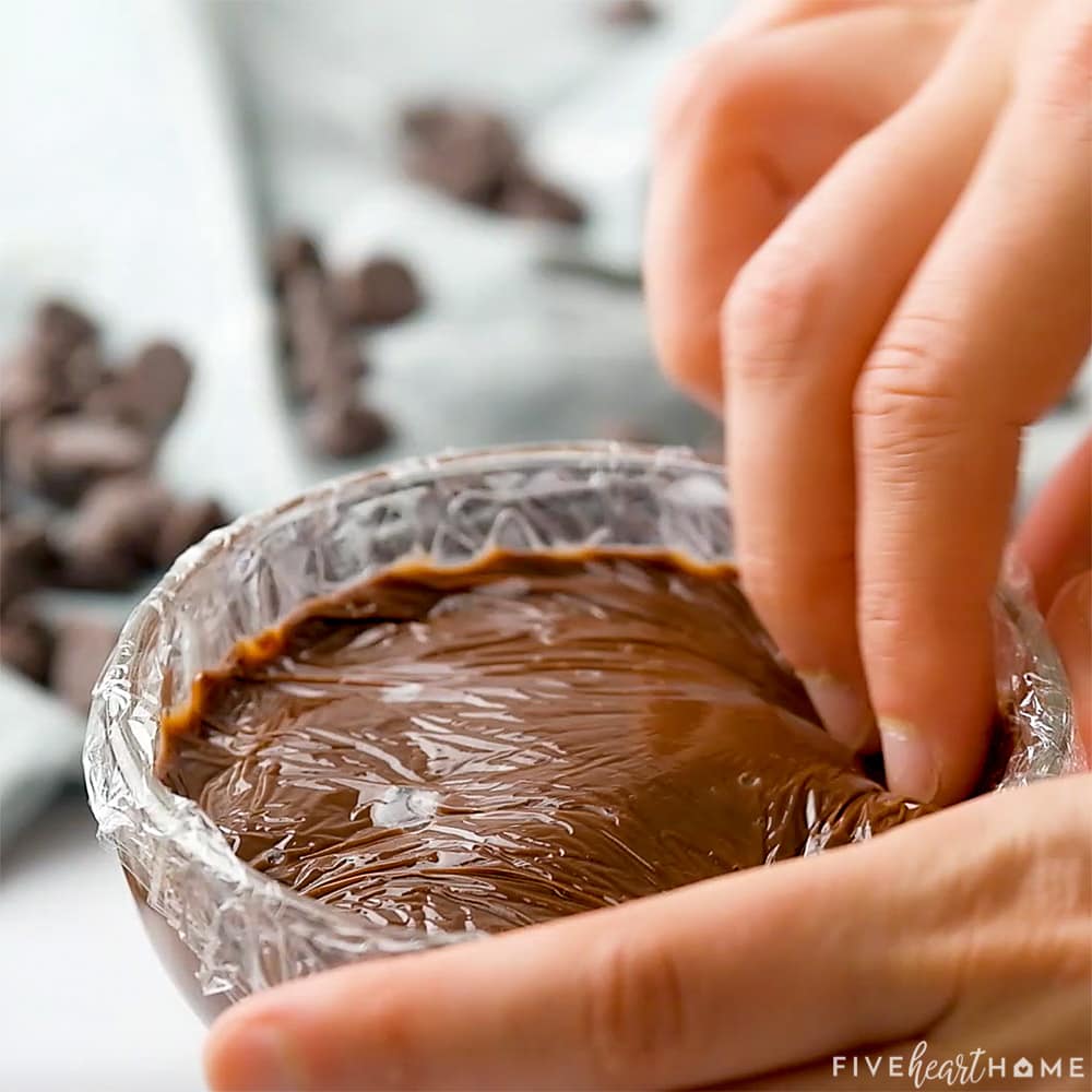 Putting plastic wrap on surface to prevent skin from forming on pudding.