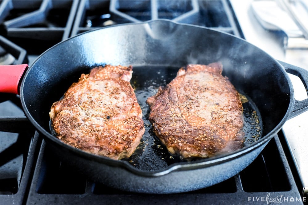 Ribyes cooking in skillet for Steak Frites recipe.