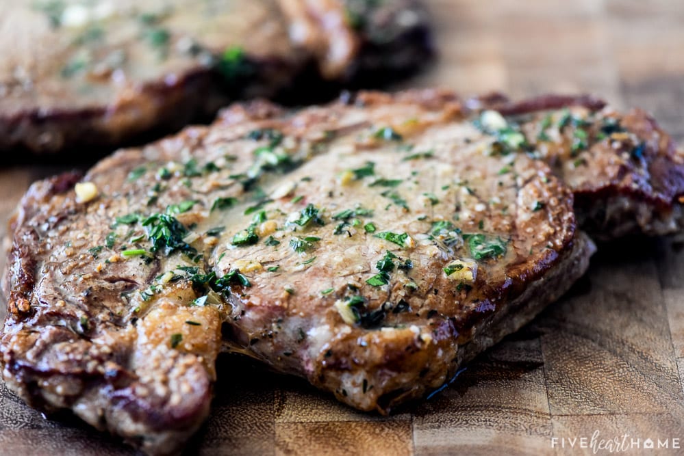 Resting steak covered in herb butter.