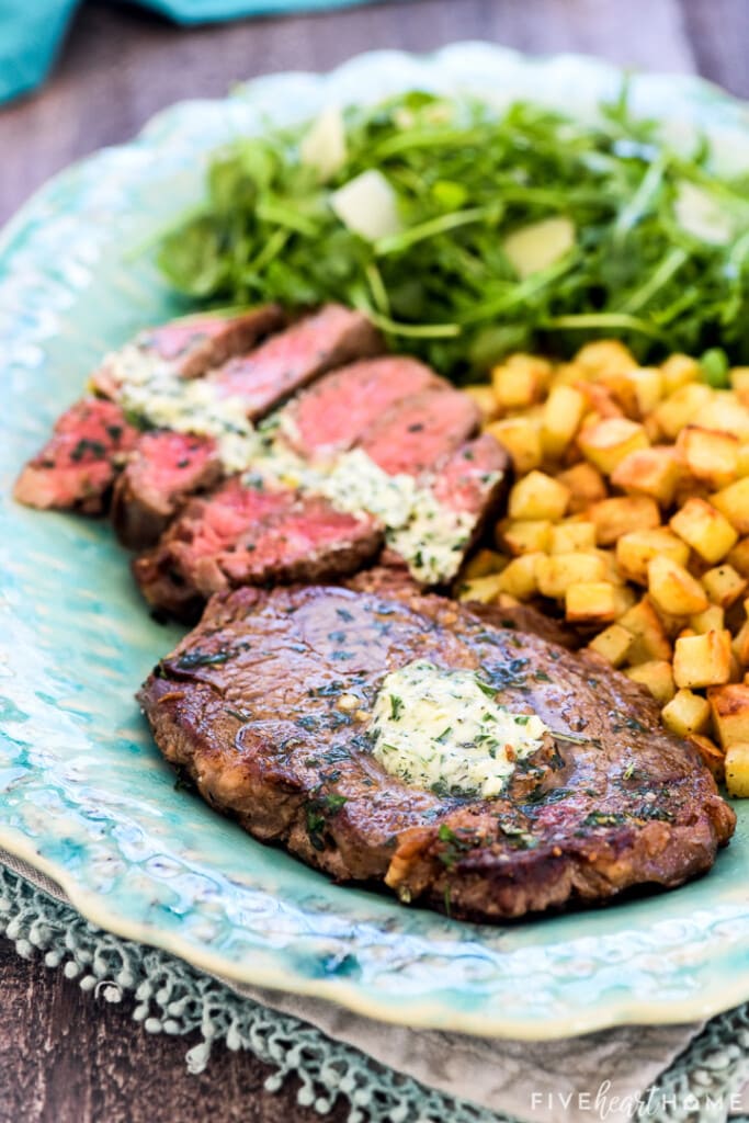 Close-up of Steak Frites ribeyes and potatoes on platter.