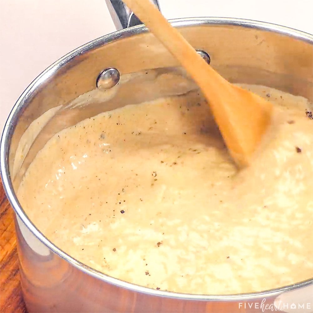 Stirring in black pepper with a wooden spoon.