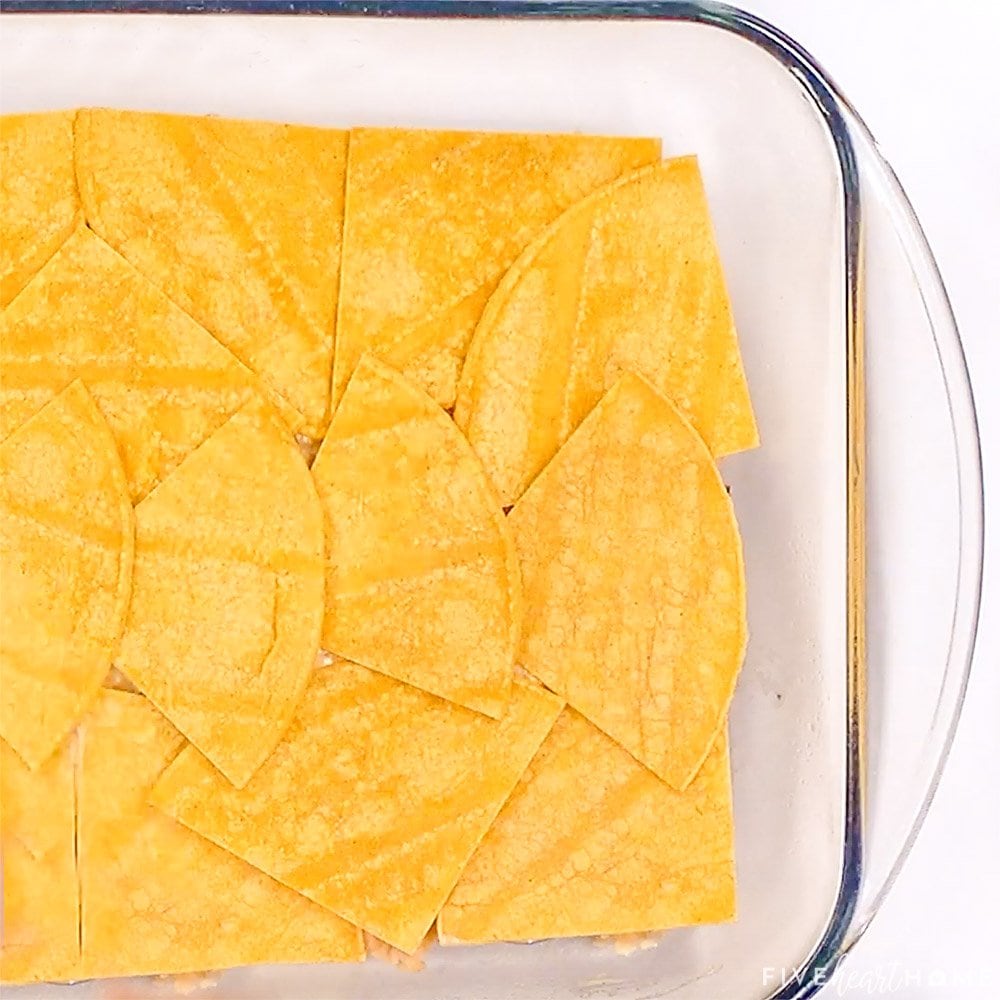 Corn tortillas arranged in baking dish.