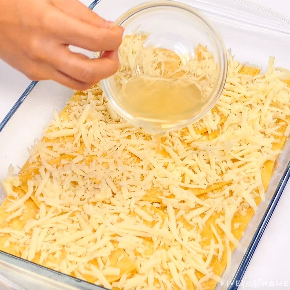 Chicken broth drizzled over first layer of Chicken Enchilada Casserole.