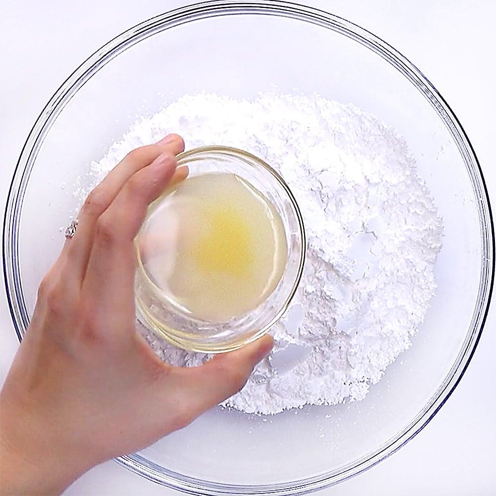 Making lemon glaze for pound cake by combining powdered sugar and lemon juice.