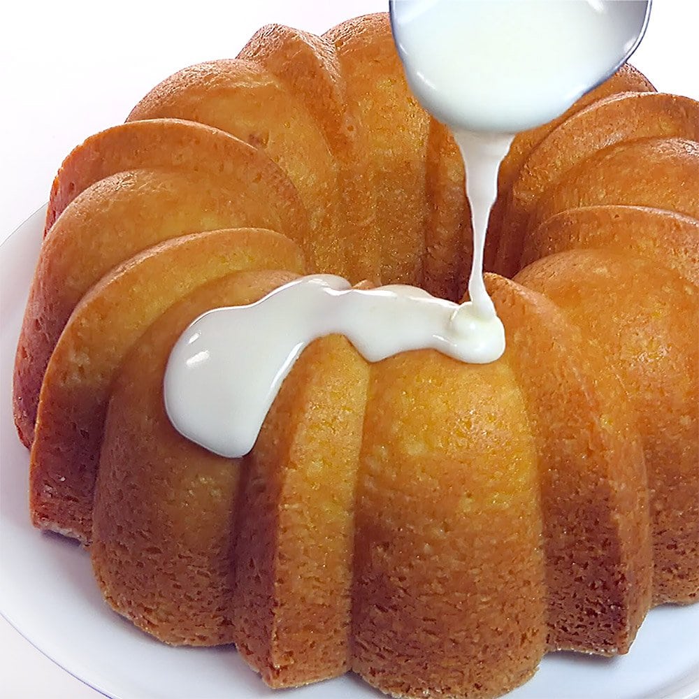 Pouring lemon glaze over Lemon Pound Cake.