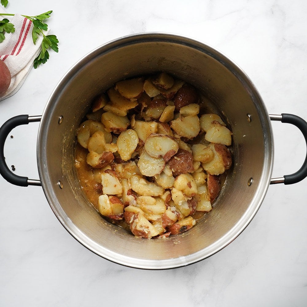 Stirring together German Potato Salad ingredients in pot.