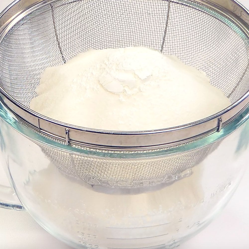 Sifting flour and cornstarch into bowl.