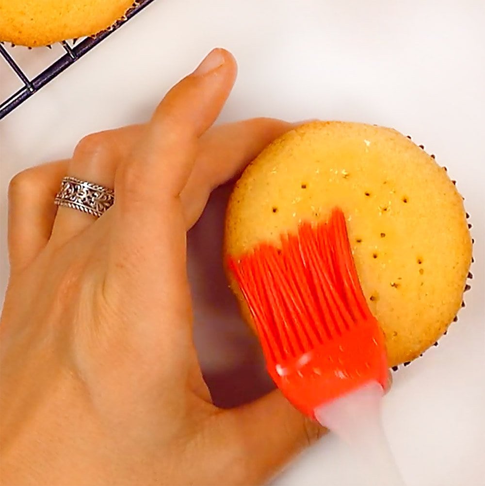 Brushing syrup on cupcake.
