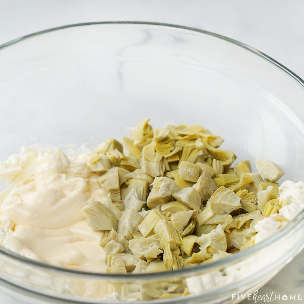 Adding mayo and artichoke hearts to bowl.