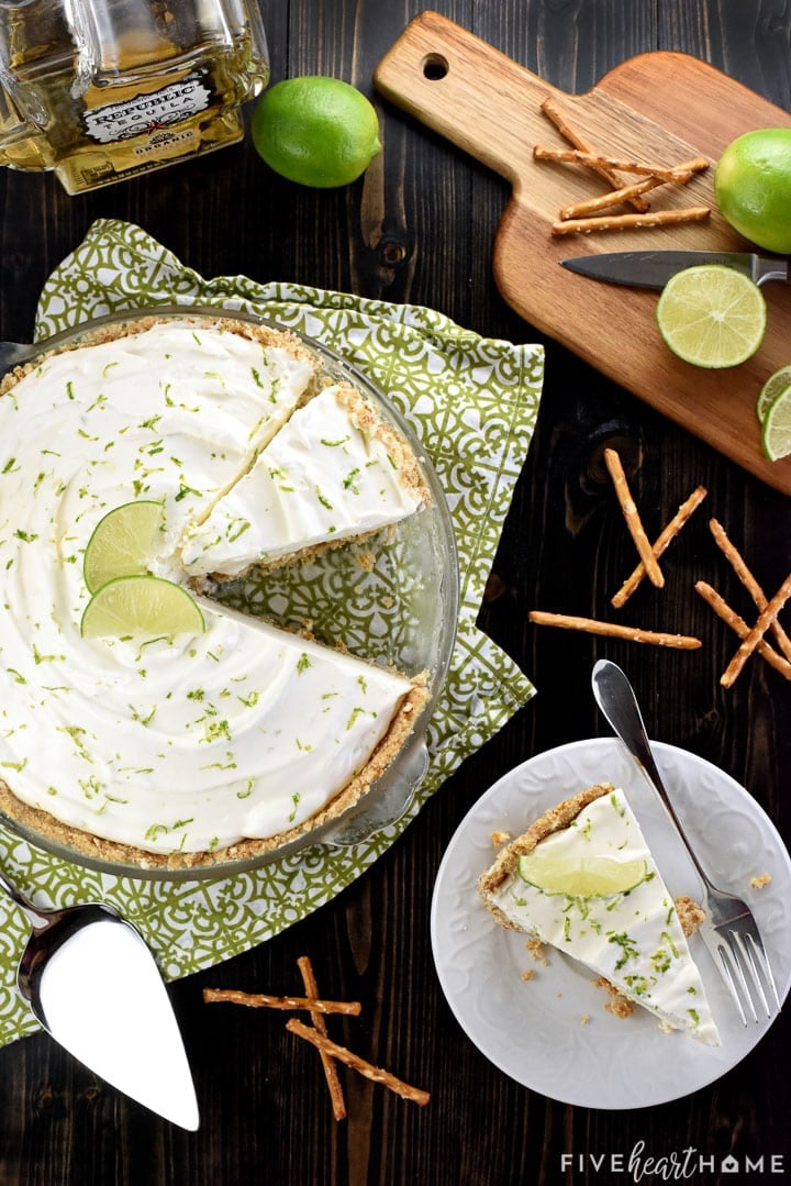 Aerial view of Frozen Margarita Pie in pan, sliced on plate, plus ingredients on table.