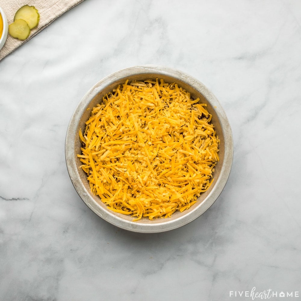Shredded cheese sprinkled over ground beef in baking dish.
