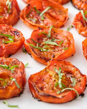 Close-up of Roasted Tomatoes topped with fresh herbs.