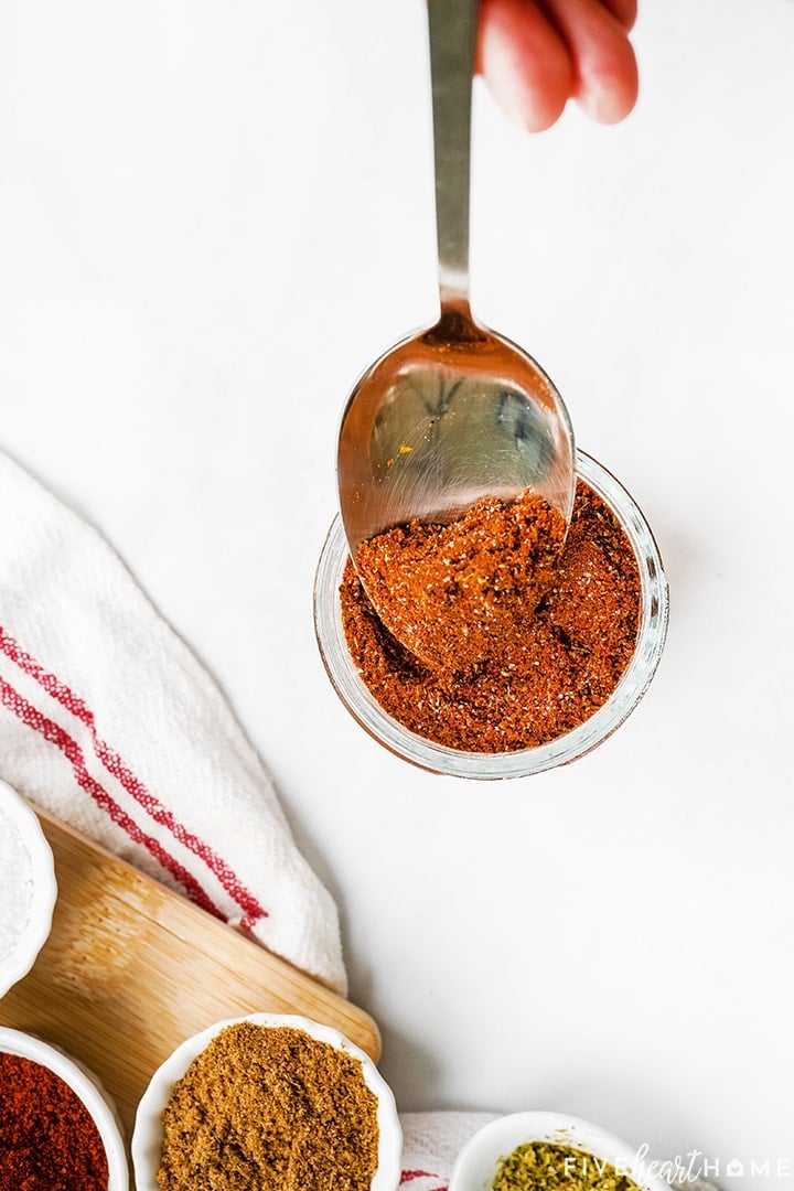 Chili Seasoning getting spooned into glass jar.