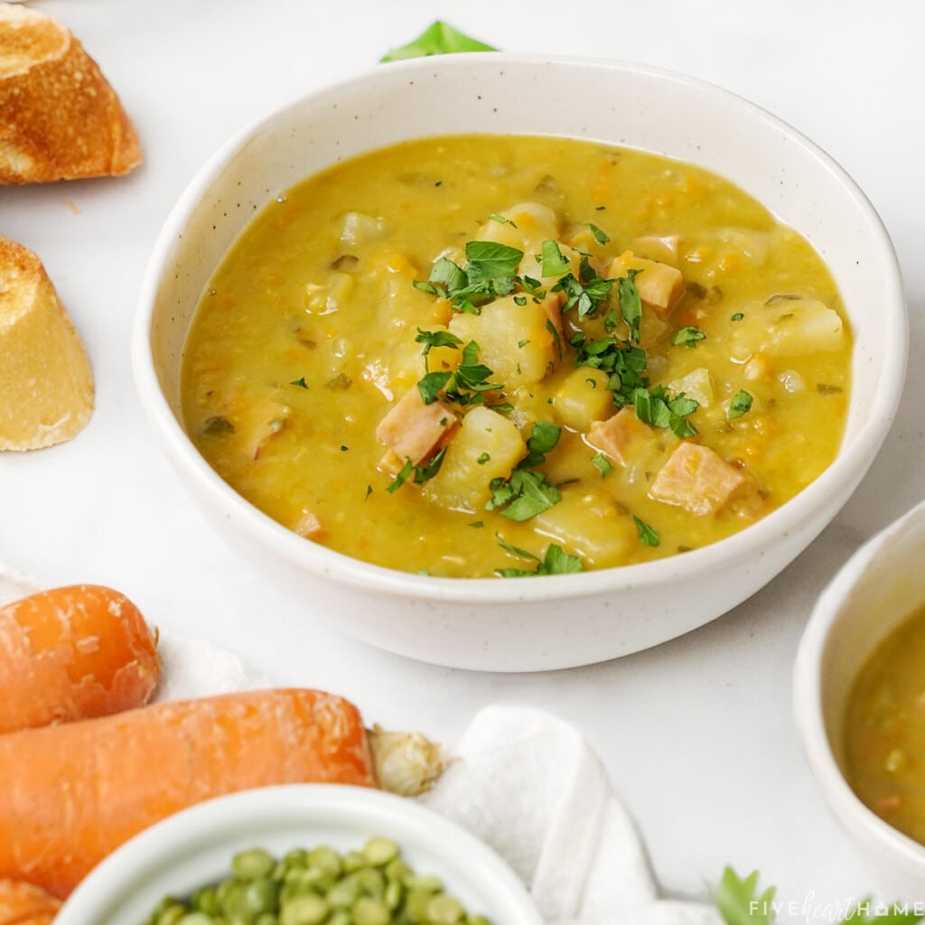 Slow Cooker Split Pea Soup in bowls with dried peas and carrots on side.