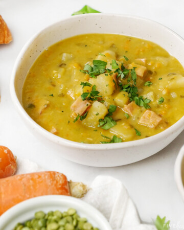 Slow Cooker Split Pea Soup in bowls with dried peas and carrots on side.