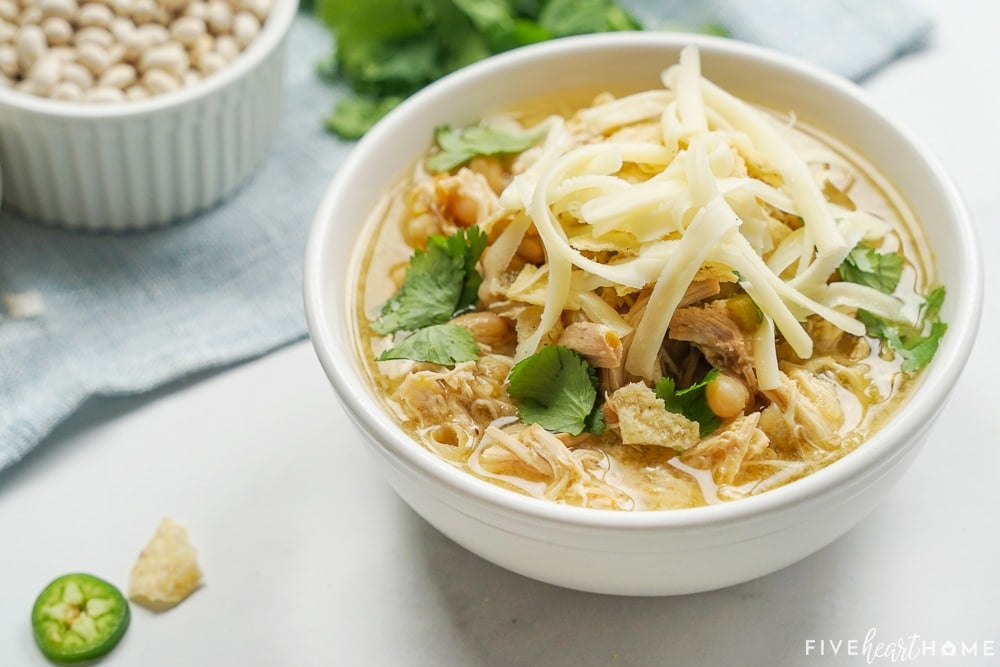 Bowl of White Bean Chicken Chili with dried beans and cilantro in background.