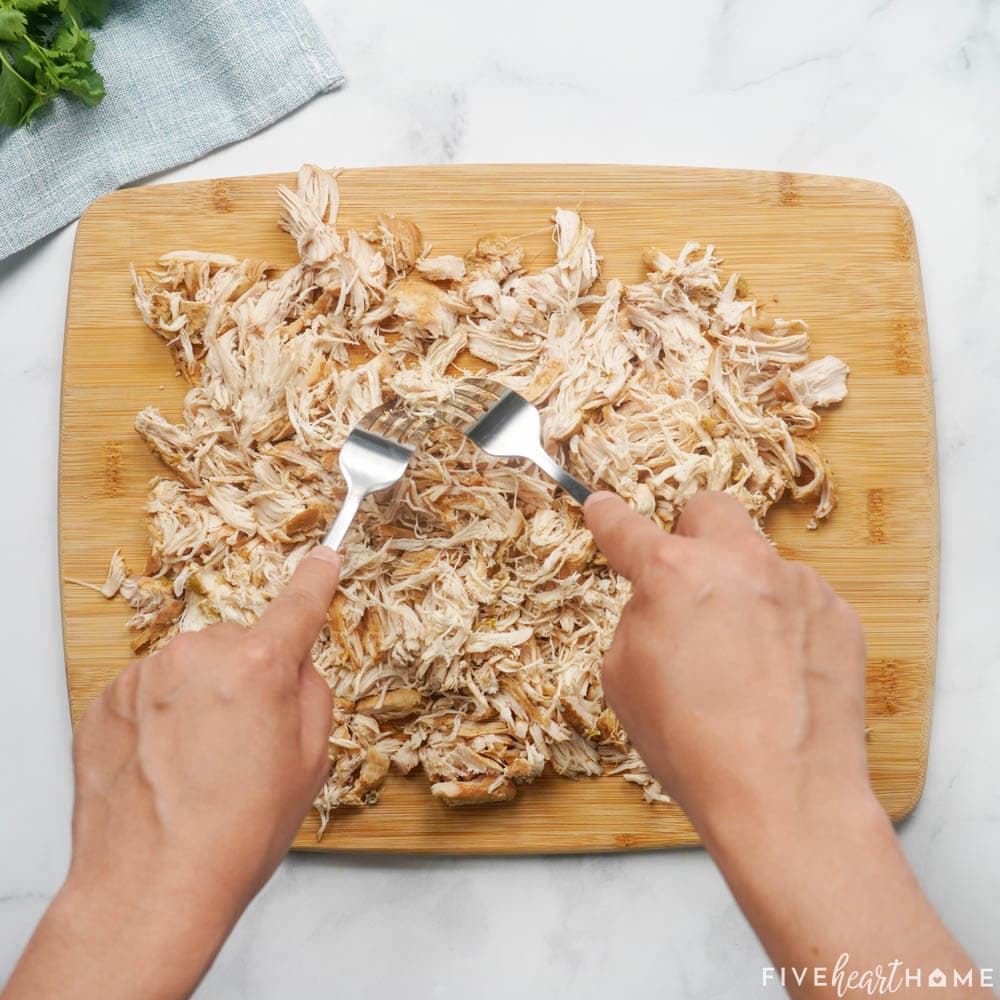 Shredding chicken breasts on cutting board.