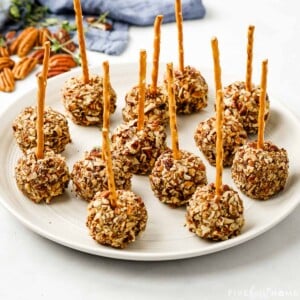 Plate of Mini Cheese Ball Bites with pecans in background.