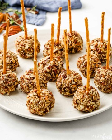 Plate of Mini Cheese Ball Bites with pecans in background.